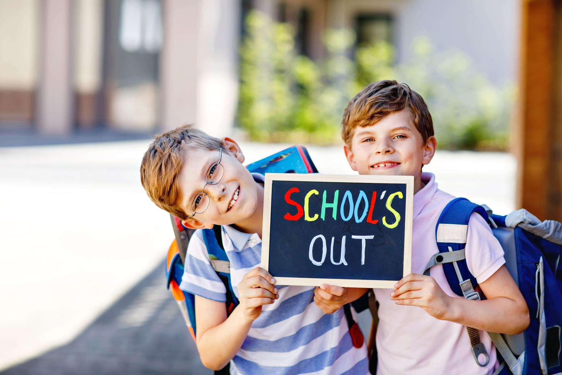 Deux petits garçons avec sac à dos ou cartable. Des écoliers sur le chemin de l’école. Des enfants, des frères et des meilleurs amis en bonne santé à l’extérieur dans la rue quittant la maison. L’école est sur un bureau de craie. Frères et 