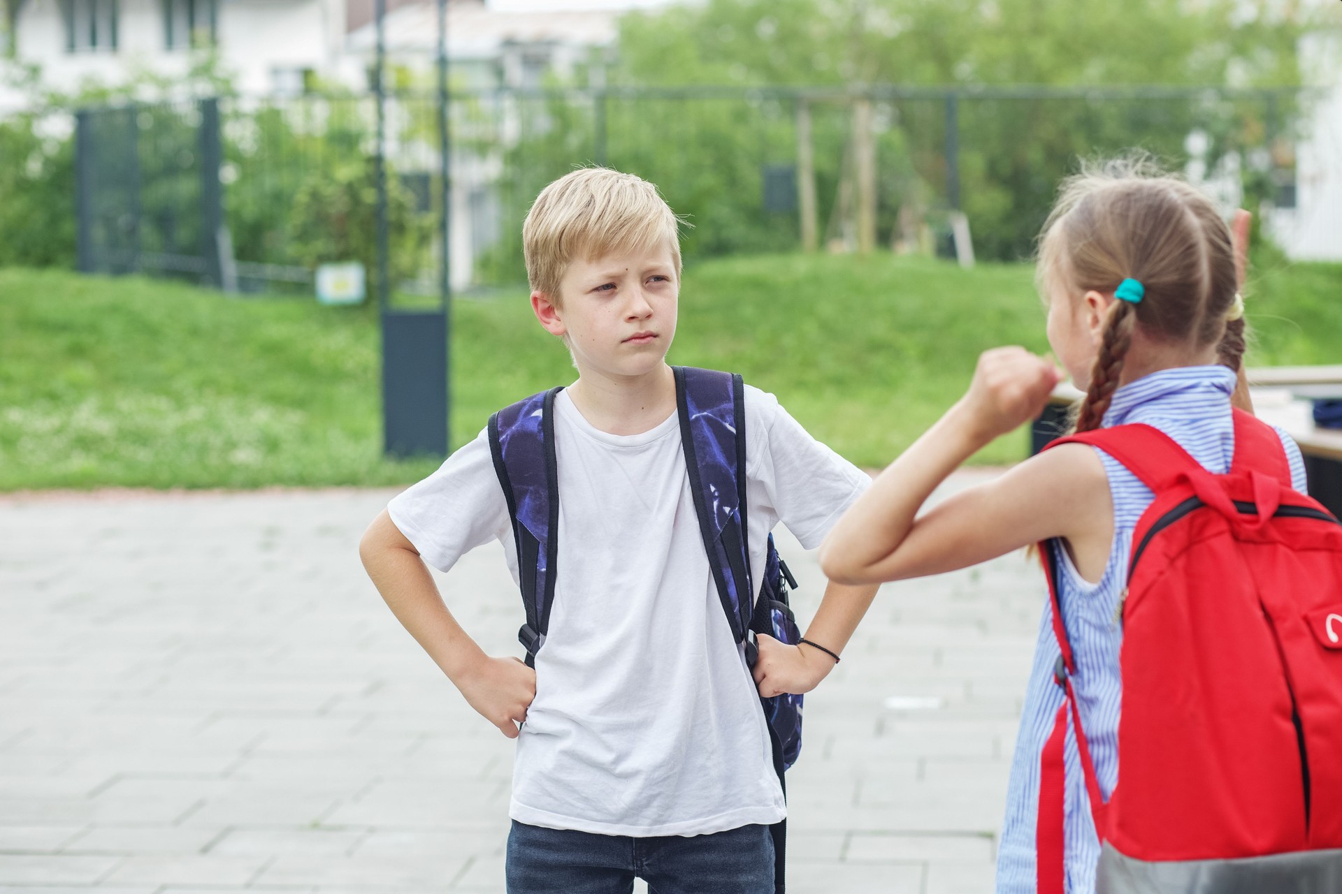 Deux enfants, camarades de classe, se disputent et crient en revenant de l’école. Conflit et émotion négative.
