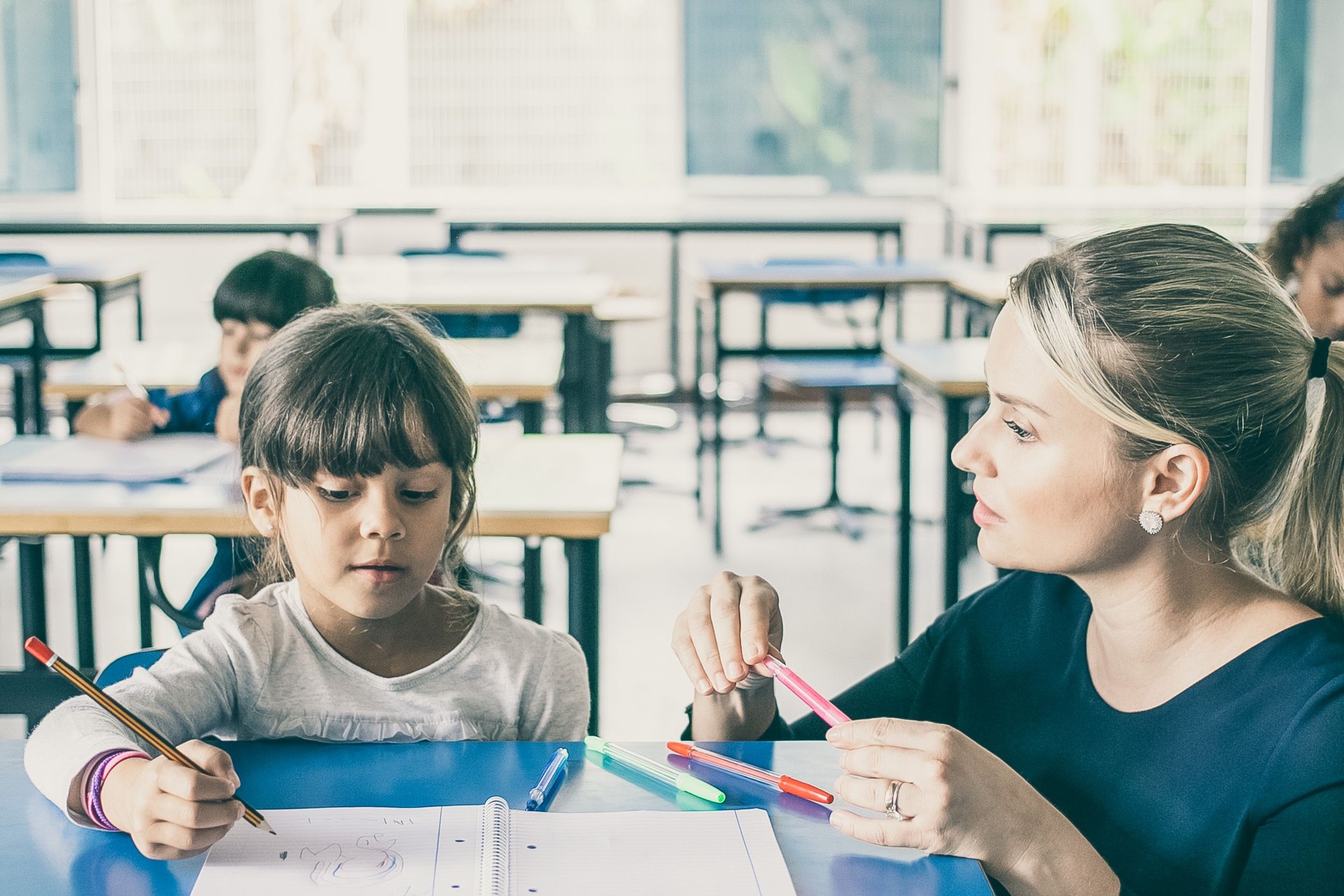 Professeur sérieux d’école primaire aidant la fille